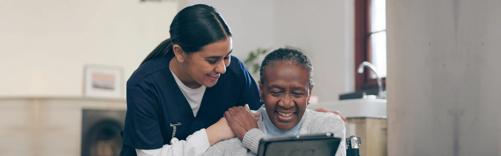 Caregiver and elderly woman looking at a tablet