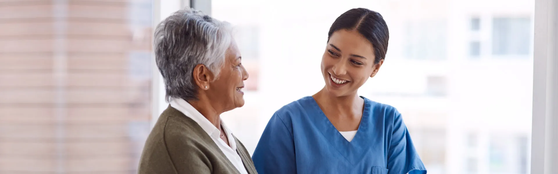 Caregiver engaging in friendly conversation with a senior - Hero Slide 1