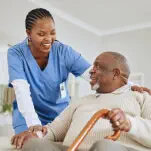 Female nurse at home fixing the room of elder woman