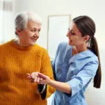 Woman smiling while holding the hands of the elder woman