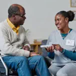 elder man and female caregiver are facing each other