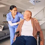 Smiling female nurse and elderly man sitting on the wheelchair